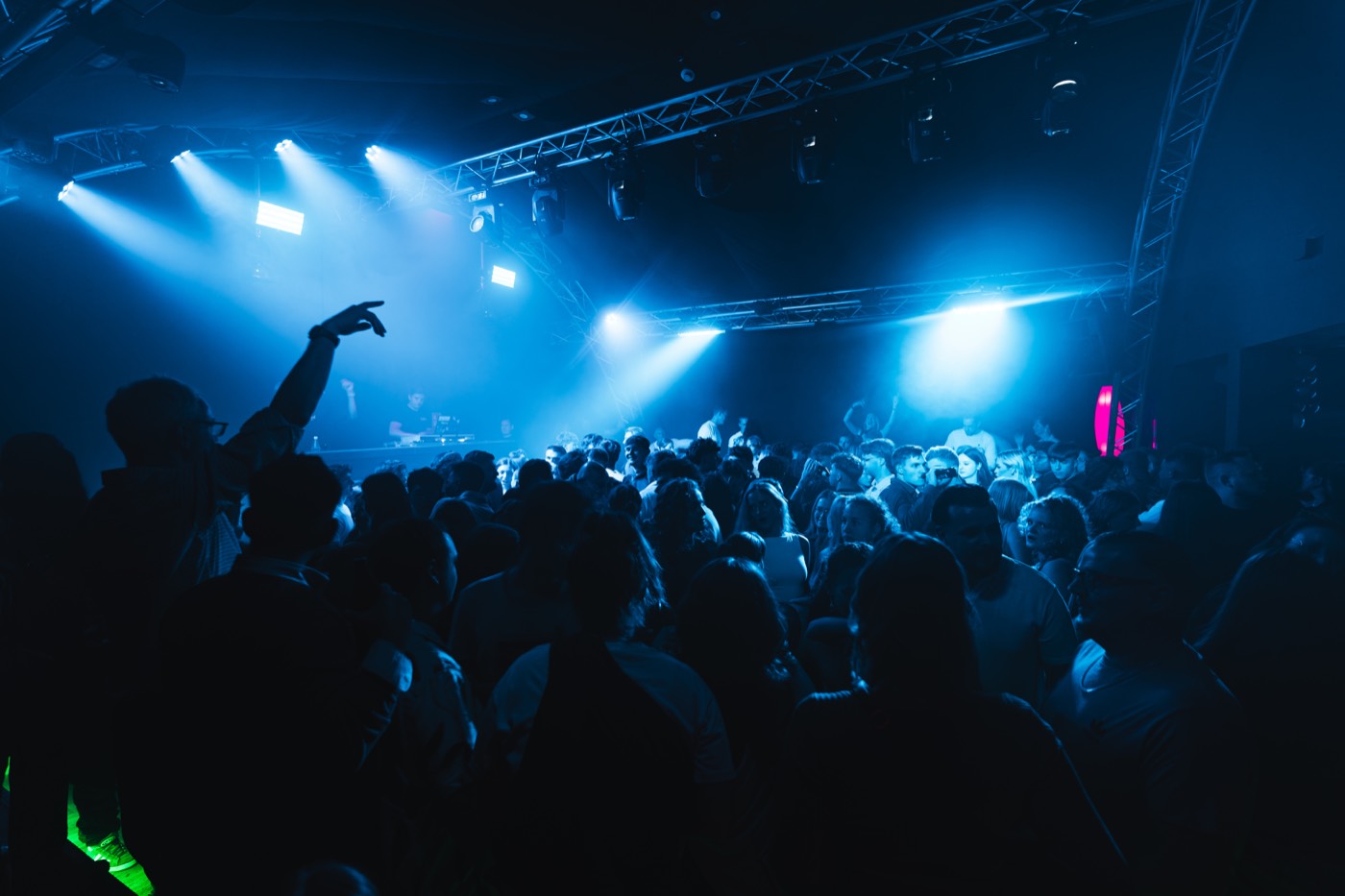 Tanzfläche im Nexxus Club Marburg, blaue Scheinwerferbahnen über der Menge, DJ-Pult im Hintergrund
